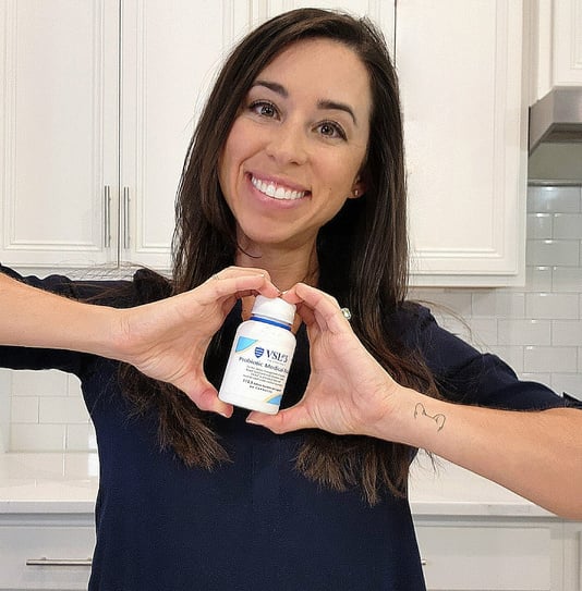 health and wellness ugc creator smiling holding a bottle of probiotics
